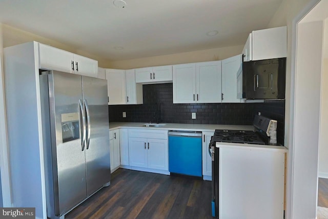 kitchen featuring tasteful backsplash, dark wood-style flooring, white cabinets, stainless steel appliances, and a sink