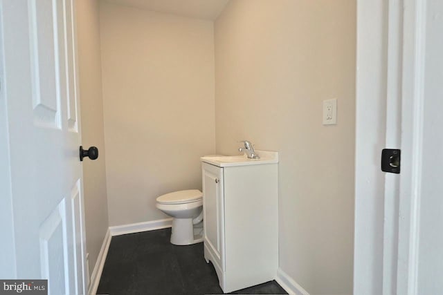 half bath with vanity, toilet, and baseboards