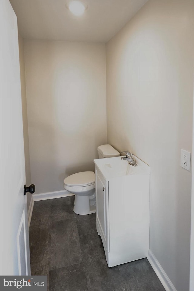 half bath with toilet, baseboards, and a sink