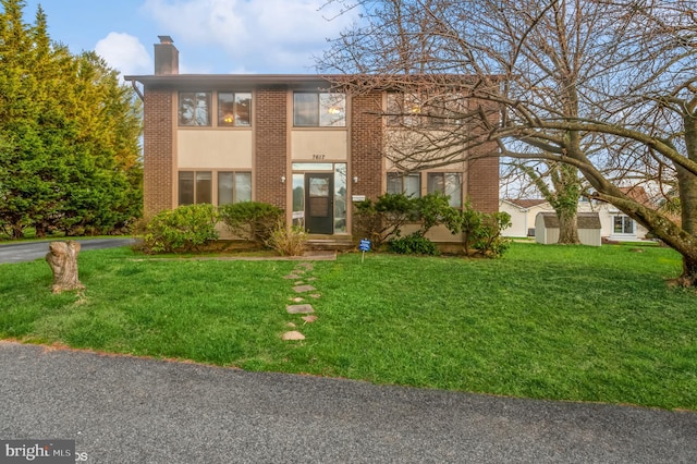 view of front of home featuring brick siding, a chimney, and a front lawn