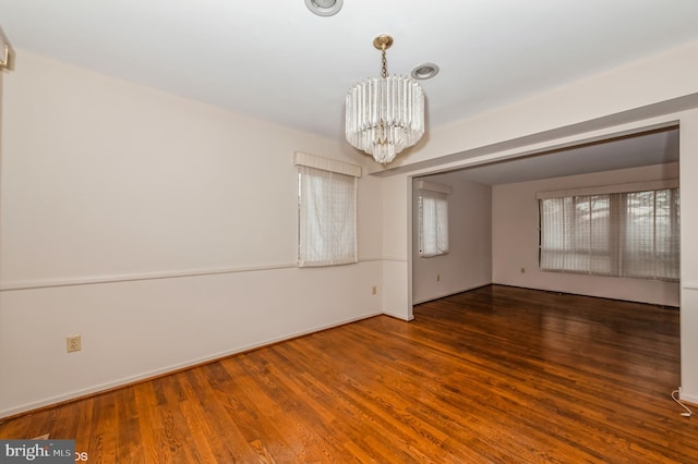 unfurnished room with an inviting chandelier and wood finished floors