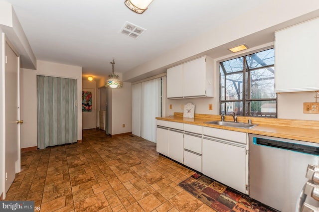 kitchen with visible vents, a sink, stone finish flooring, stainless steel dishwasher, and white cabinets