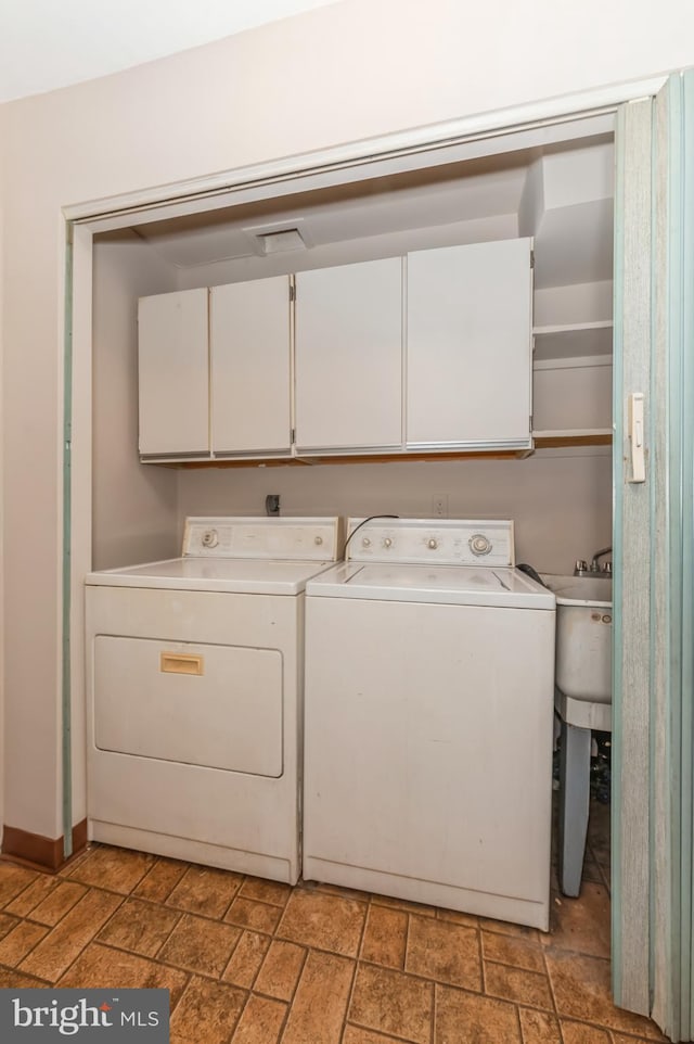 clothes washing area featuring cabinet space, baseboards, stone finish floor, and separate washer and dryer