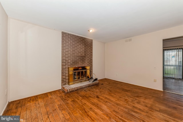 unfurnished living room with visible vents, a fireplace, and hardwood / wood-style floors