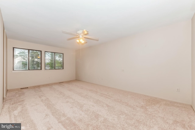 carpeted spare room featuring visible vents and ceiling fan