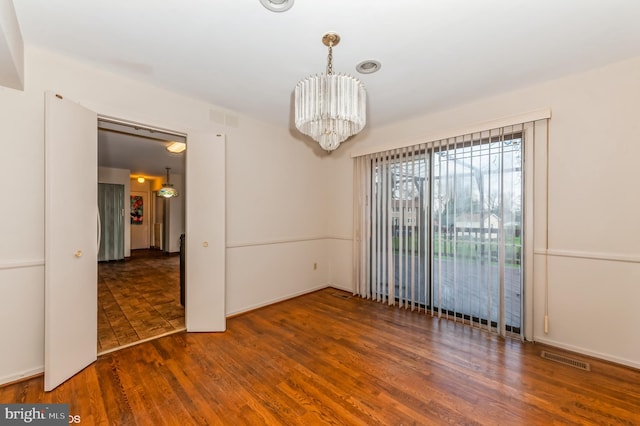 spare room featuring visible vents, an inviting chandelier, and wood finished floors