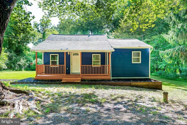 view of front of home featuring a porch, a forest view, and a front yard