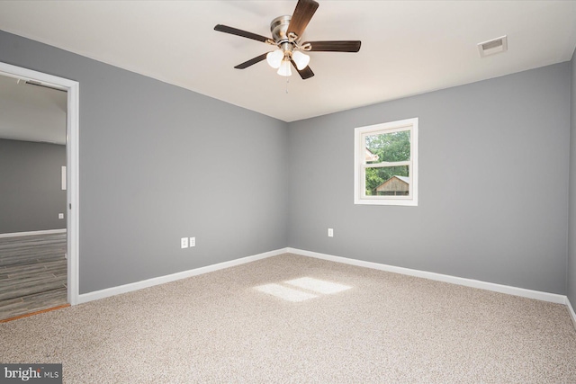 carpeted spare room with visible vents, baseboards, and a ceiling fan