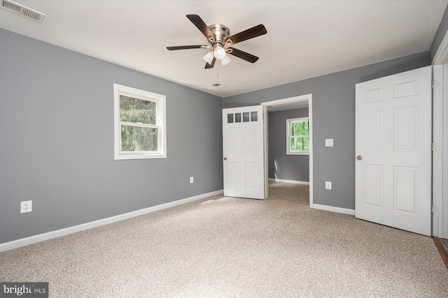 unfurnished bedroom featuring visible vents, multiple windows, carpet, and baseboards