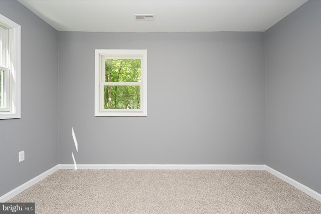 carpeted spare room with visible vents and baseboards