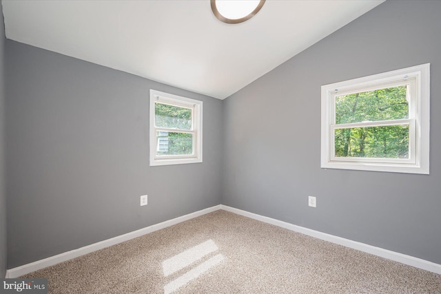 carpeted empty room with baseboards and vaulted ceiling