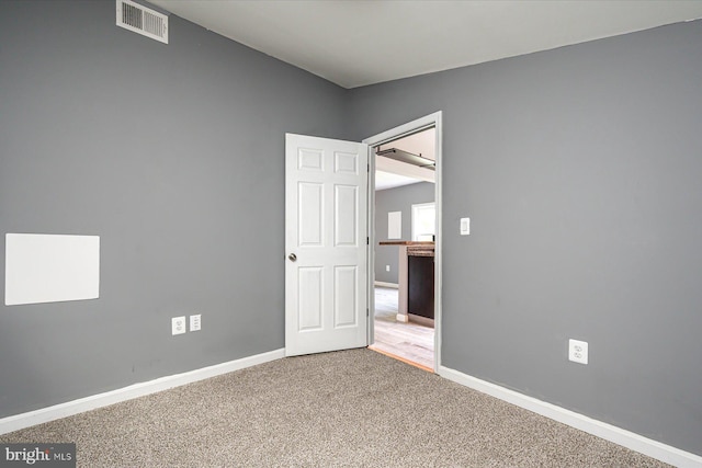 carpeted empty room featuring visible vents and baseboards