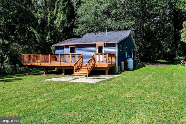 rear view of property with a wooden deck, a yard, and a view of trees