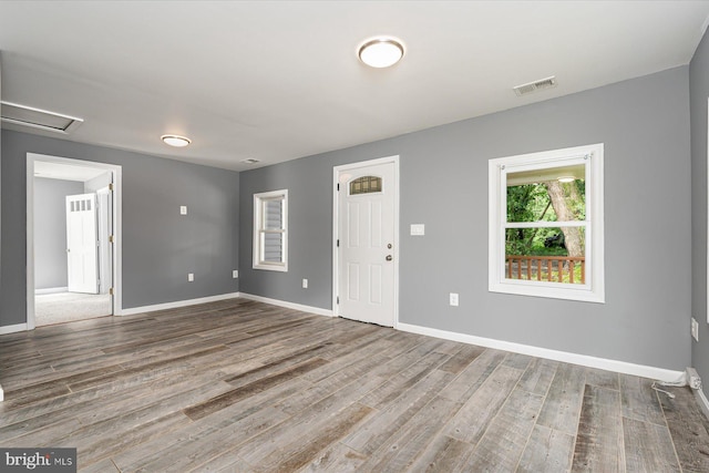 spare room with attic access, wood finished floors, visible vents, and baseboards