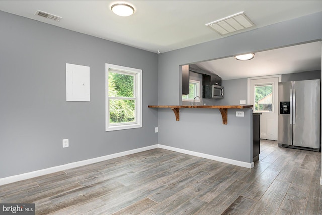 kitchen with wood finished floors, baseboards, visible vents, stainless steel appliances, and a kitchen breakfast bar