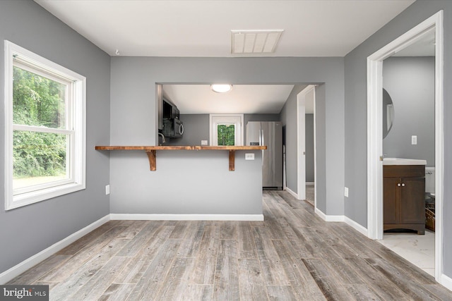 kitchen with light wood finished floors, visible vents, appliances with stainless steel finishes, and baseboards