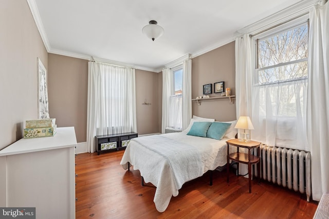 bedroom featuring crown molding, radiator, and wood finished floors