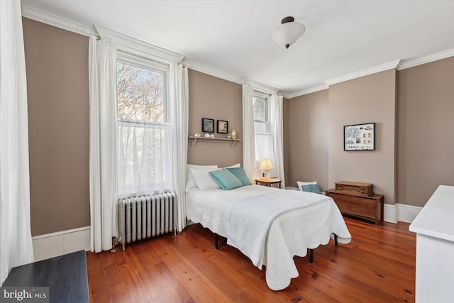 bedroom featuring crown molding, radiator heating unit, wood finished floors, and baseboards