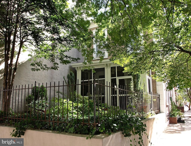 view of property exterior with a sunroom and fence