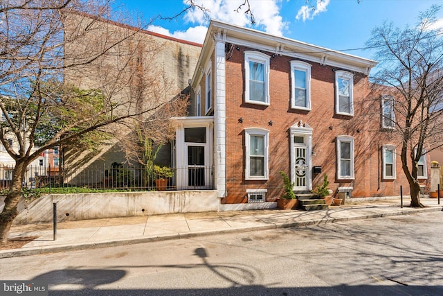 view of front facade with brick siding and fence