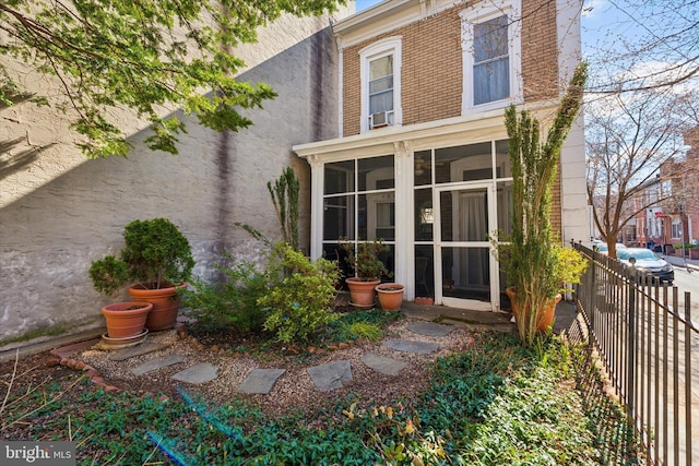 back of property with fence and a sunroom