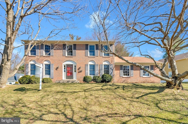 colonial inspired home featuring brick siding and a front lawn