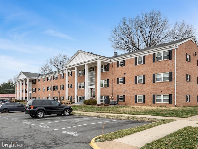 view of building exterior featuring central AC unit and uncovered parking