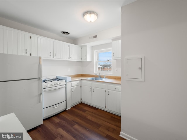 kitchen featuring white appliances, a sink, light countertops, dark wood-type flooring, and white cabinetry