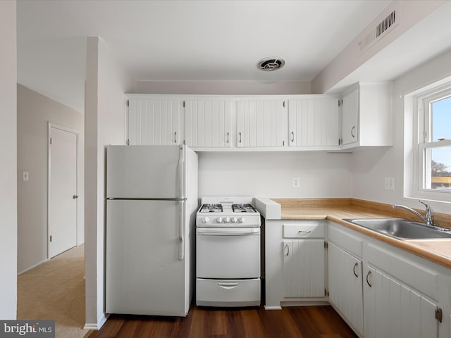 kitchen featuring white appliances, light countertops, visible vents, and a sink