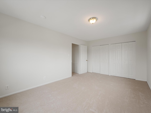 unfurnished bedroom with baseboards, multiple closets, and carpet floors