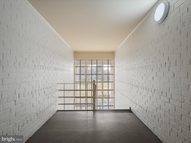 unfurnished room with brick wall and ornamental molding