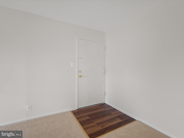 spare room featuring baseboards and dark colored carpet