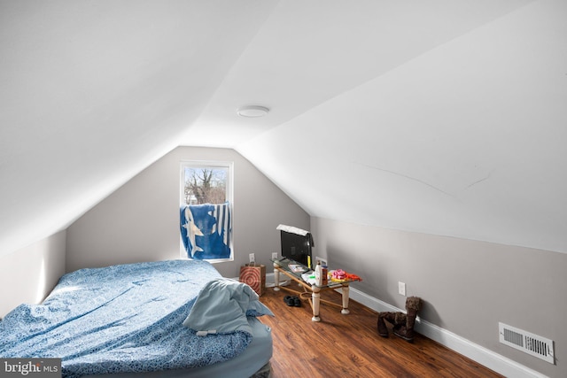 bedroom with vaulted ceiling, wood finished floors, visible vents, and baseboards