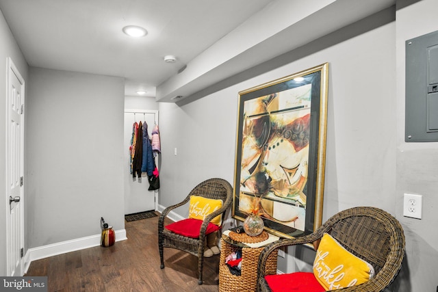 living area featuring electric panel, baseboards, and wood finished floors