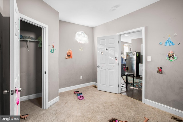 interior space with carpet, visible vents, freestanding refrigerator, and baseboards