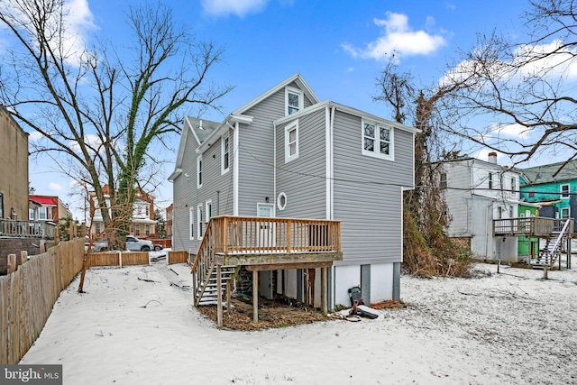 snow covered rear of property featuring stairway, a deck, and fence