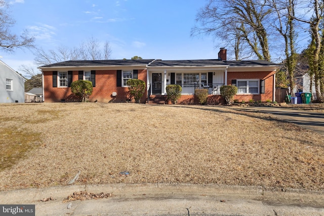 single story home with brick siding, a porch, a chimney, and a front yard