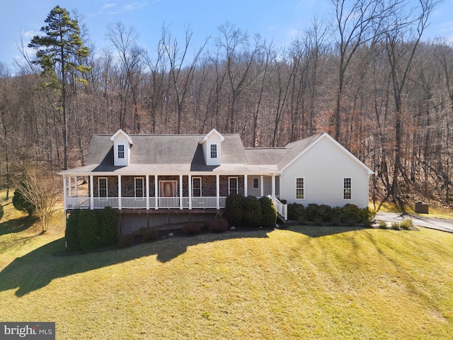 view of front facade with a porch, a forest view, and a front lawn