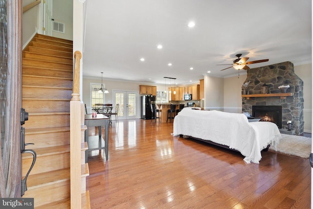 bedroom with visible vents, black fridge, light wood-style flooring, and ornamental molding