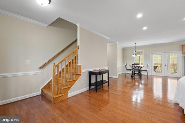 stairway with french doors, crown molding, baseboards, and wood finished floors