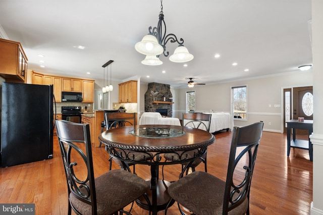 dining space featuring baseboards, recessed lighting, a fireplace, ornamental molding, and light wood-type flooring