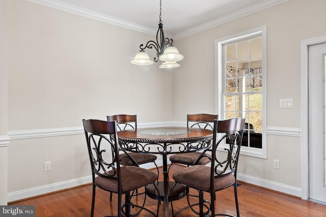 dining room with a chandelier, ornamental molding, baseboards, and wood finished floors