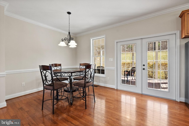 dining area with french doors, wood-type flooring, an inviting chandelier, crown molding, and baseboards