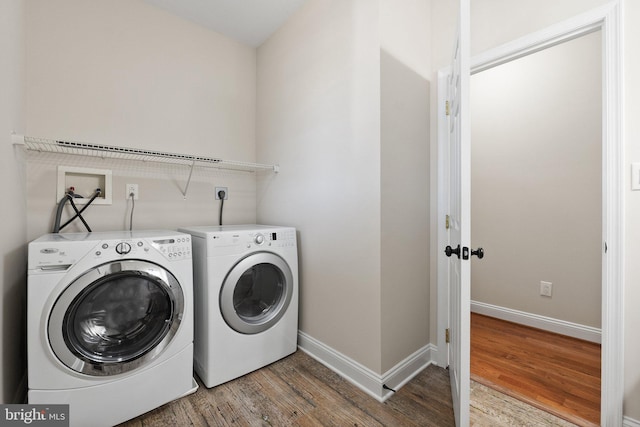 clothes washing area featuring washer and dryer, laundry area, baseboards, and light wood-type flooring