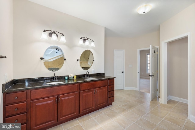 full bathroom with tile patterned flooring, double vanity, baseboards, and a sink