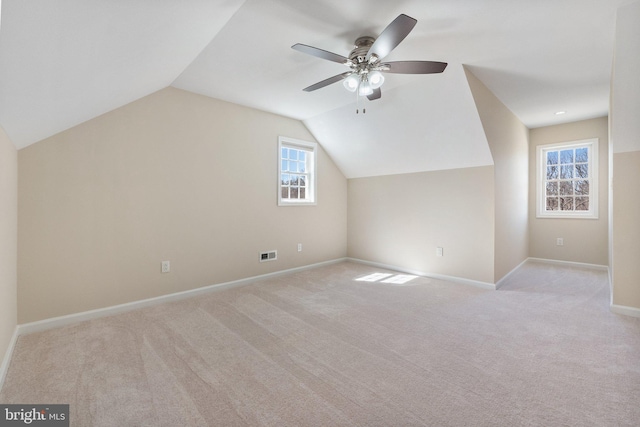 additional living space featuring visible vents, carpet flooring, baseboards, ceiling fan, and vaulted ceiling