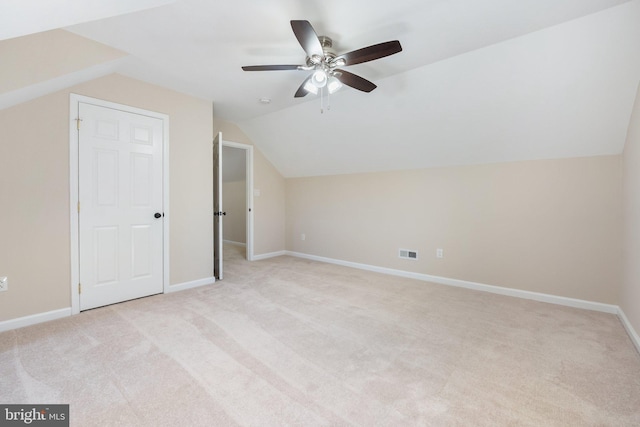 additional living space featuring visible vents, light carpet, baseboards, and vaulted ceiling