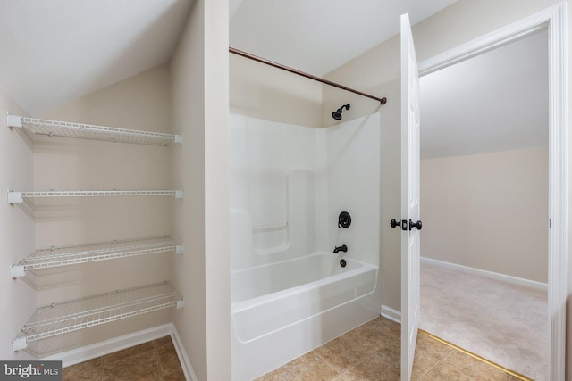 bathroom featuring tile patterned flooring, lofted ceiling, bathing tub / shower combination, and baseboards