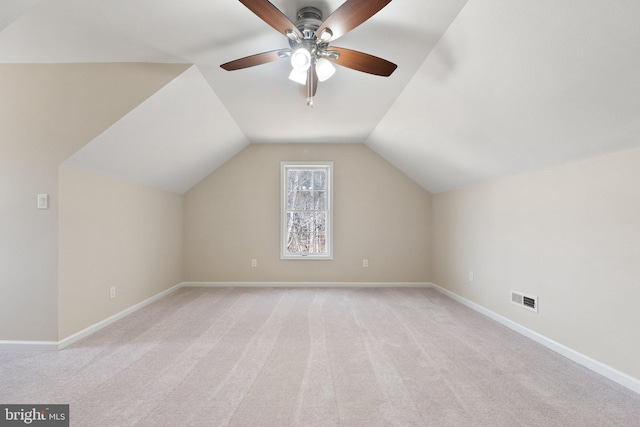 additional living space with visible vents, light carpet, baseboards, ceiling fan, and vaulted ceiling