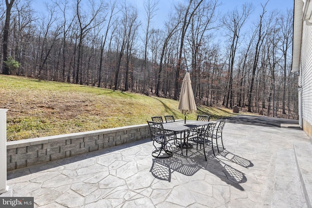 view of patio / terrace featuring a view of trees and outdoor dining space